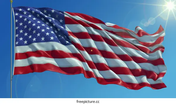American flag waving in the wind against a bright blue sky with sun rays