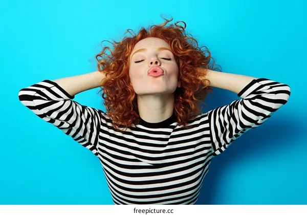 Woman with Red Curly Hair in Striped Top against Blue Background