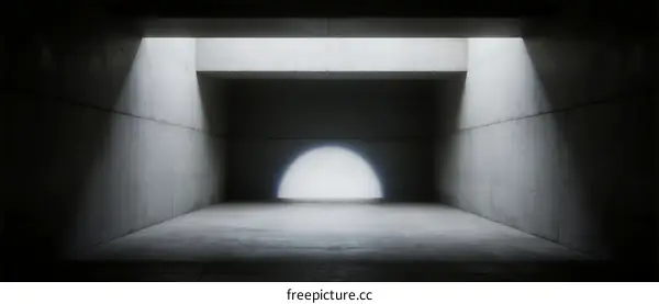 A dark concrete room with a bright circular light source at the end