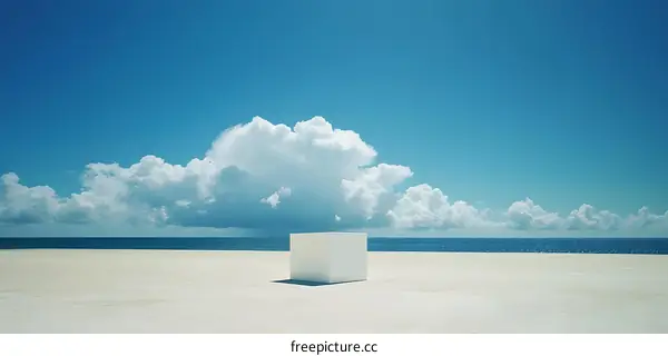 White Cube on a Sandy Beach with Blue Sky and White Clouds