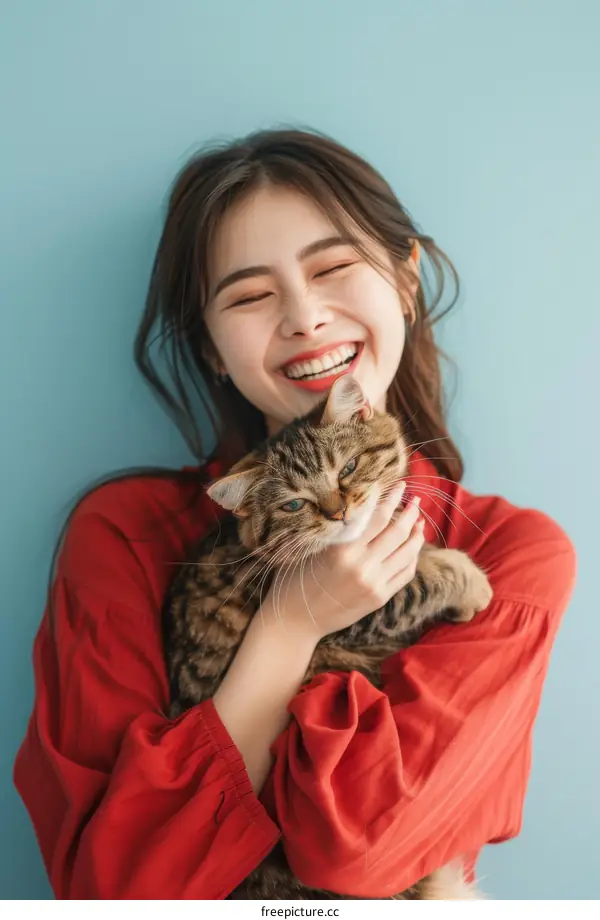 A young Asian woman is smiling and hugging a cat
