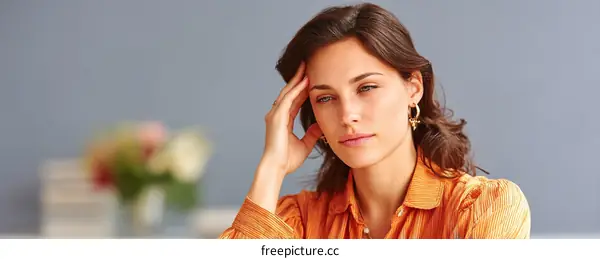 Thoughtful Woman in Orange Blouse