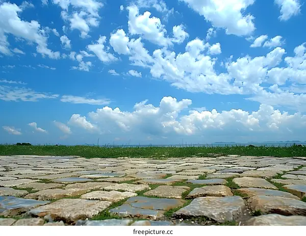 Blue Sky with White Fluffy Clouds Over Green Grass and Stone Path