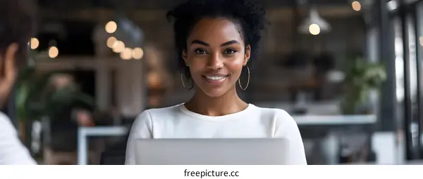 African American Woman Smiling While Using Laptop In Office