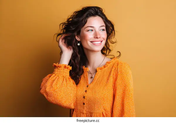 Smiling Woman in an Orange Dress Against a Mustard Background