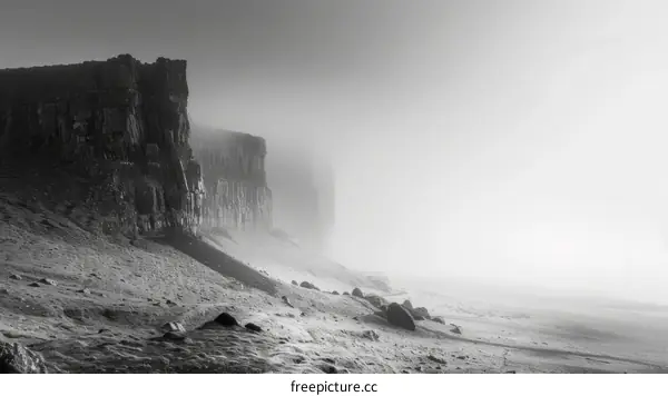 Black and white photo of a rocky cliff face shrouded in mist