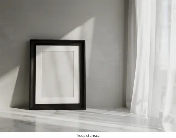 Empty black picture frame placed near white curtain on gray wall
