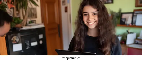 Young Woman with Long Hair Smiles While Holding a Tablet