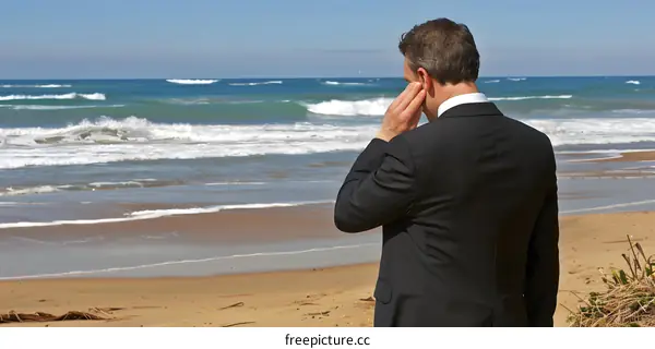 Man in Suit Standing on Beach with Ocean in Background