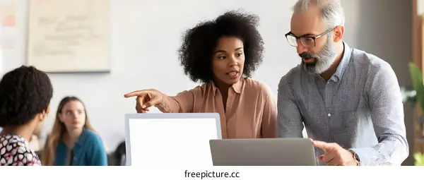 Two Business People Talking in Front of Laptop