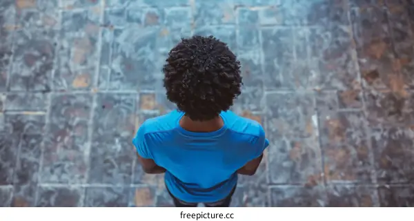 Black man wearing blue shirt from behind