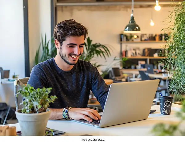 Smiling Man Working on Laptop in Modern Office