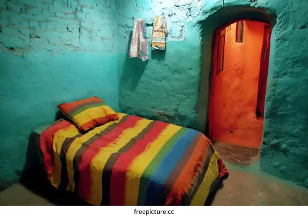 Colorful Striped Bed in a Room with Turquoise Walls and an Orange Doorway