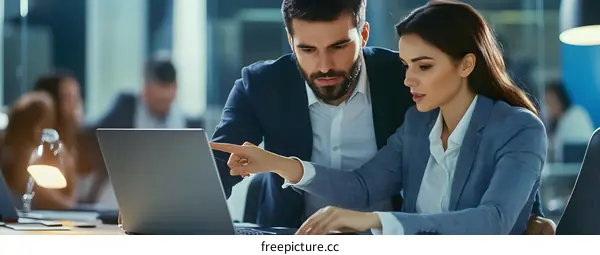 Two Business Colleagues Discussing Work On Laptop