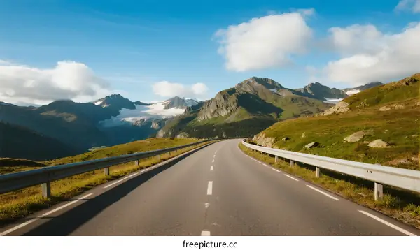Scenic road winding through mountainous landscape under clear blue sky