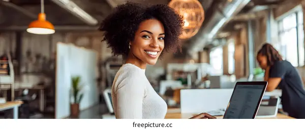 Smiling African American Woman Working on Laptop in Modern Office