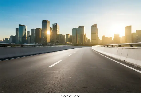 Sunlit urban road with modern city skyline in the background