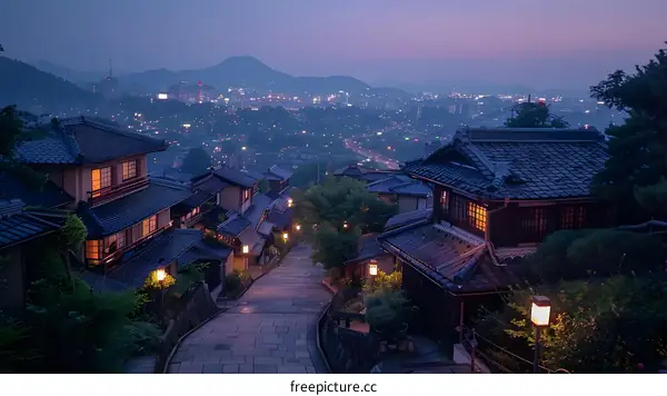 A long and winding road leads through a traditional Japanese village with tiled houses and paper lanterns.