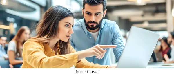 Young Business Couple Collaborating On Project Using Laptop