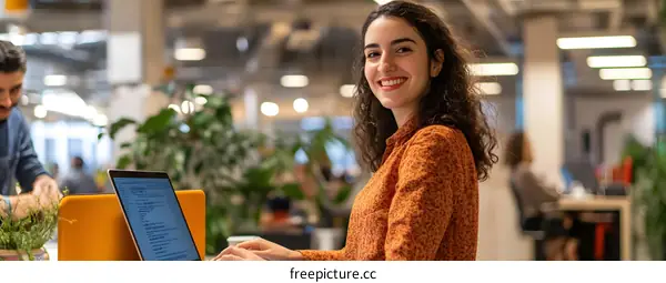 Smiling Woman Working on Laptop in Modern Office