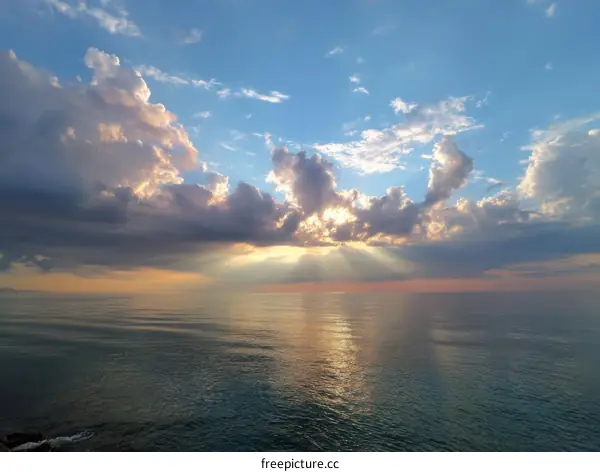 Sunset rays piercing through dramatic clouds over the sea