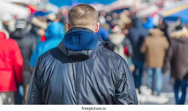 Man in Blue Jacket Walking Among Crowd