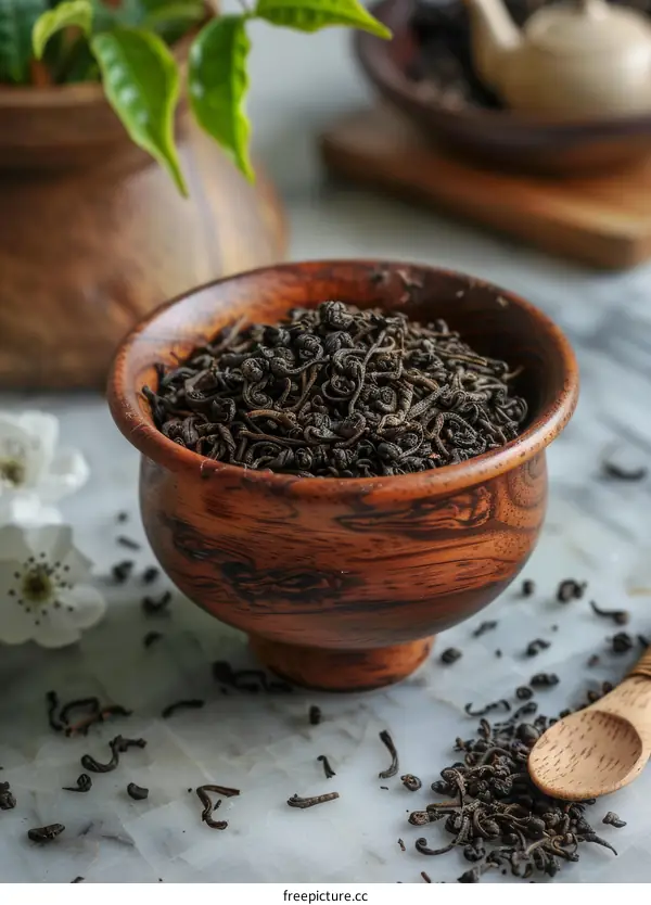 Black Tea Leaves with White Flowers in a Wooden Bowl