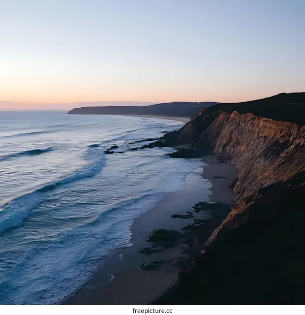 Aerial View of Coastal Cliffs and Ocean Waves at Sunset