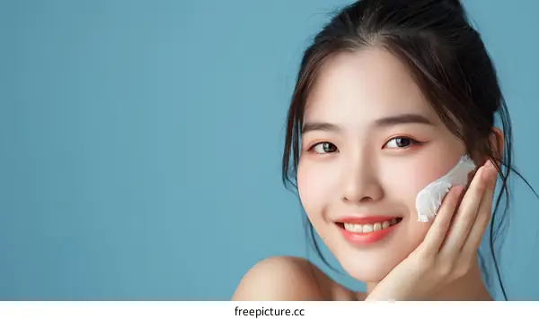 Smiling Asian Woman Applying Face Mask on Blue Background