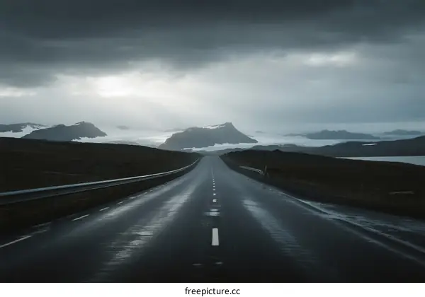 A long road stretching under a cloudy sky with distant mountains