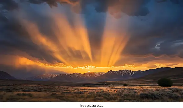 Golden Sunset Rays Through Clouds Over Mountains