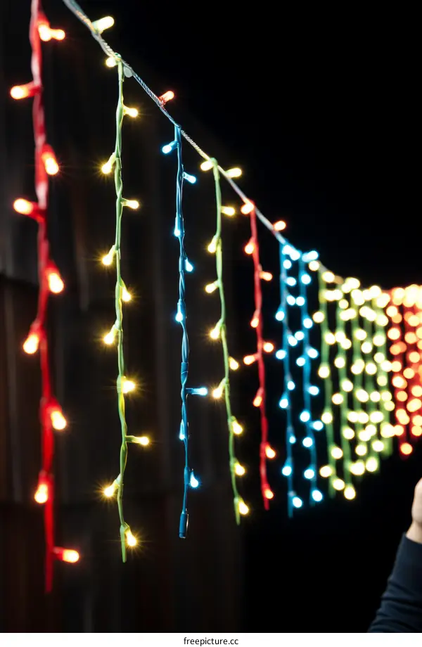 Person holding a string of multicolored lights in the dark