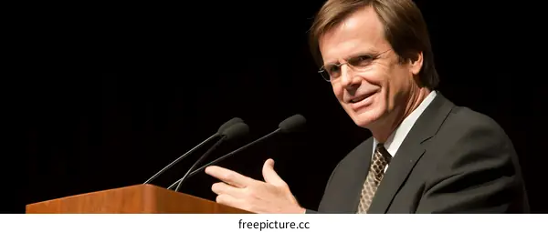 Man in Suit Speaking at a Podium with a Microphone