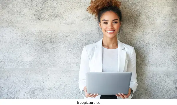 Smiling Woman Holding Laptop against a Concrete Wall