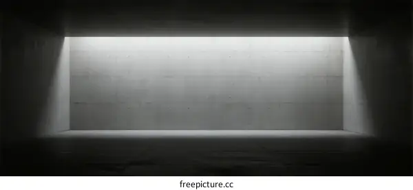 A dark room with a bright light source illuminating a concrete wall