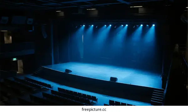 Blue stage lights illuminating empty performance space with seats