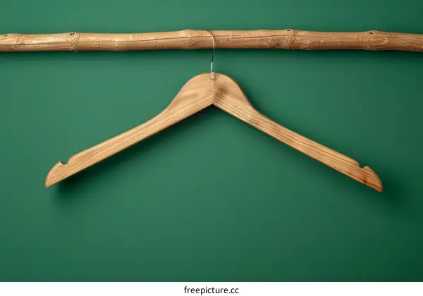 Single wooden clothes hanger on green background