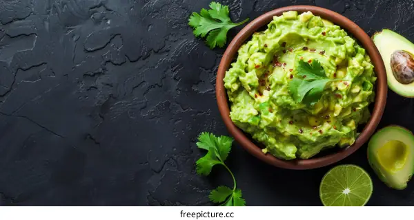 Homemade guacamole in a bowl with lime and cilantro