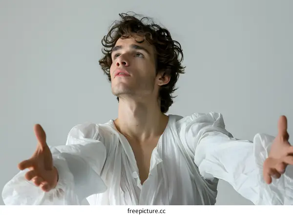 Portrait of a young male ballet dancer with curly brown hair and blue eyes, wearing a white shirt