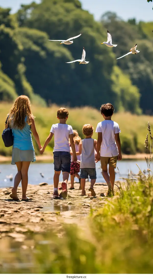 Family of five walking on a rocky riverbank with seagulls flying overhead