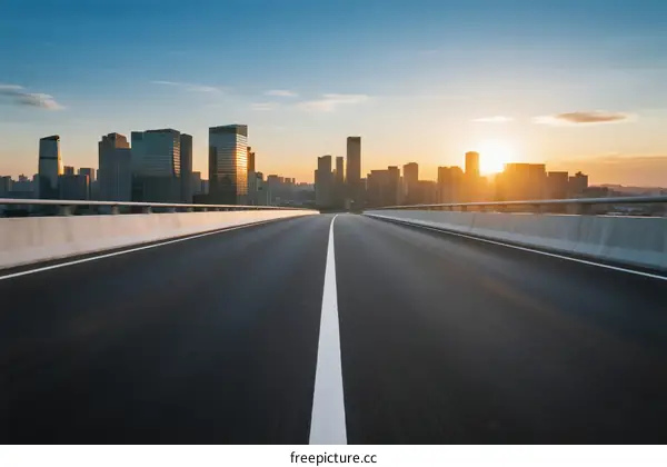 Sunset over modern city with empty road in foreground