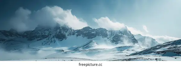 A Wide Panoramic Shot of a Snow-capped Mountain Range Under a Blue Sky