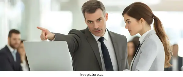 Businessman Pointing at Laptop Screen with Colleague