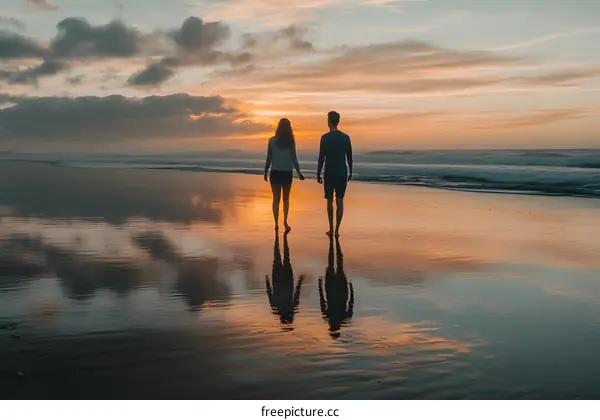 Couple Walking on Beach at Sunset with Reflections in the Sand