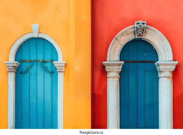 Two Blue Doors With White Frames on Bright Orange and Red Walls