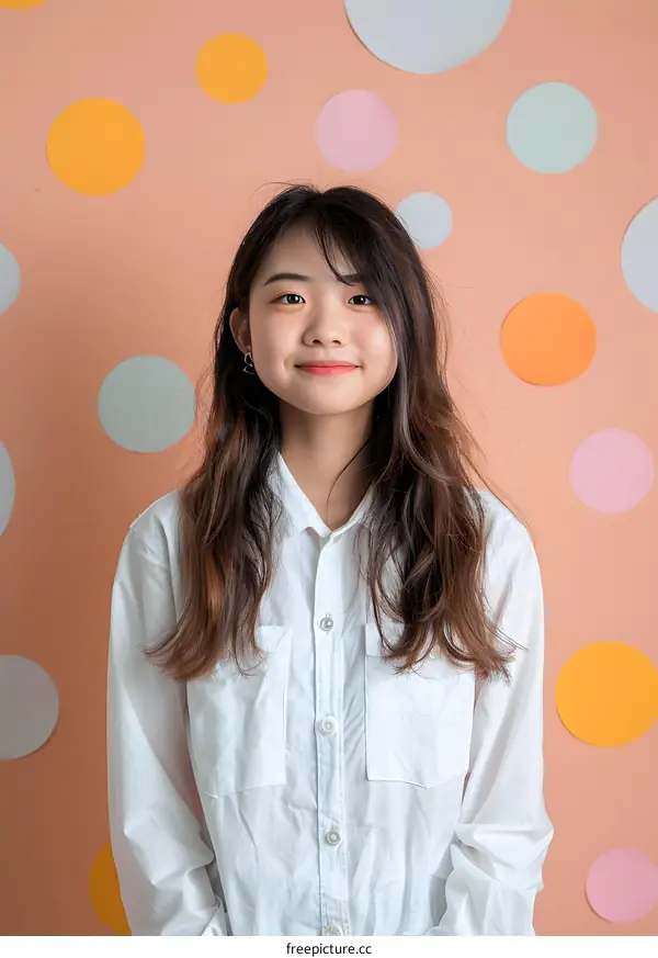 Smiling Asian Woman Wearing a White Shirt Against a Polka Dot Background
