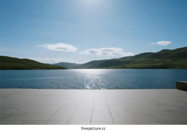 A serene lake reflecting sunlight under clear blue sky