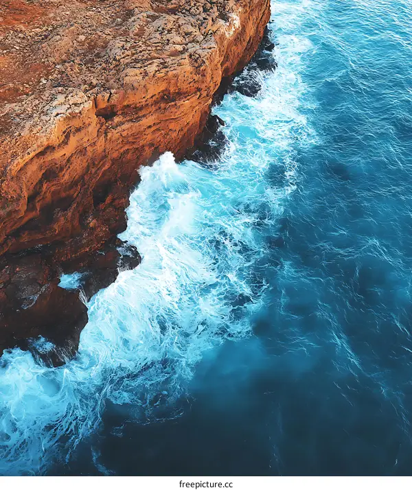 Aerial View of Ocean Waves Crashing Against Rocky Coastline