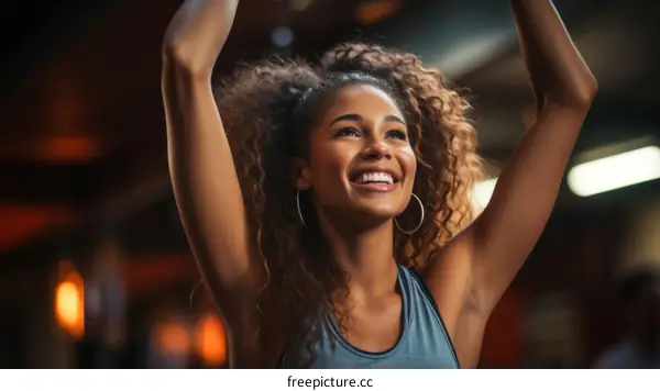 A young woman of African descent is dancing in a club with her arms in the air