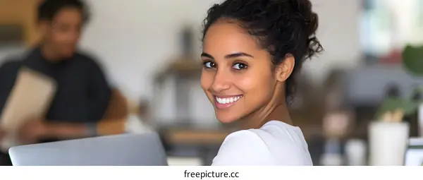 Smiling Woman Looking Over Shoulder While Working on Laptop